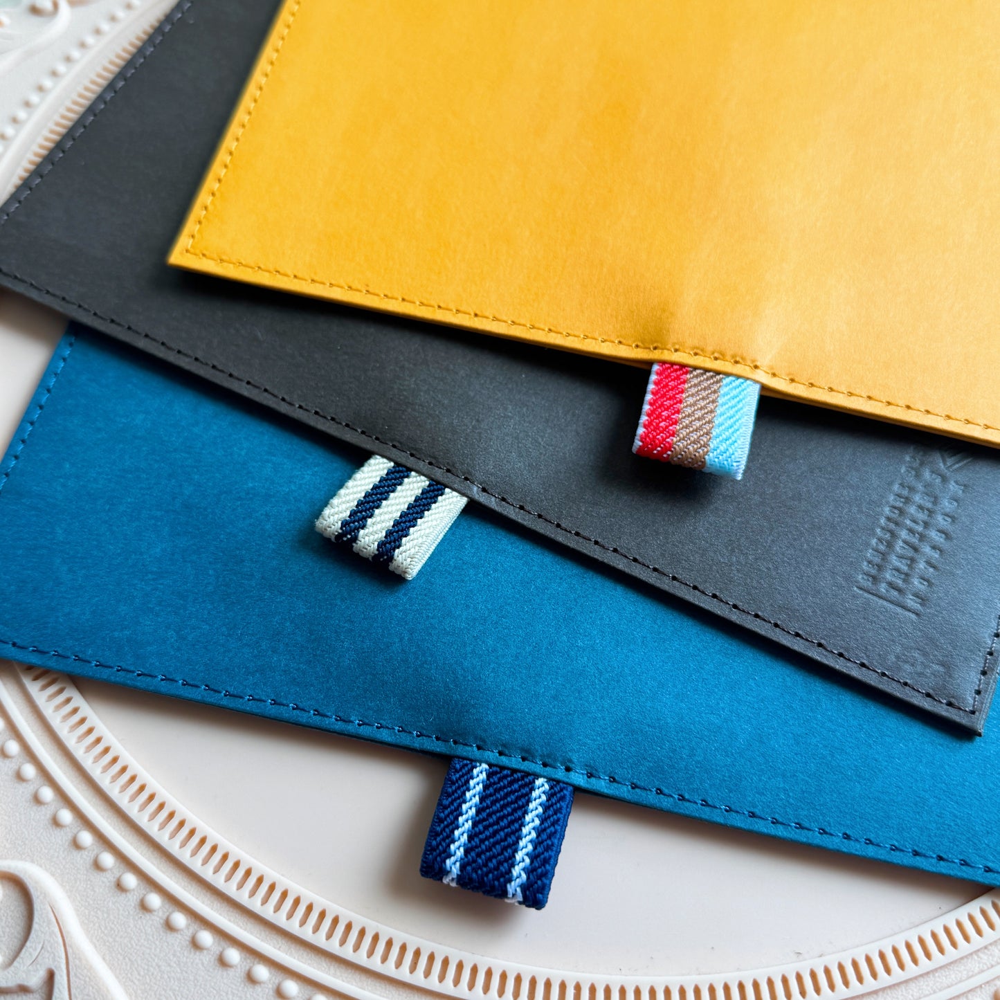 Three colorful fabric pouches stacked on a textured surface