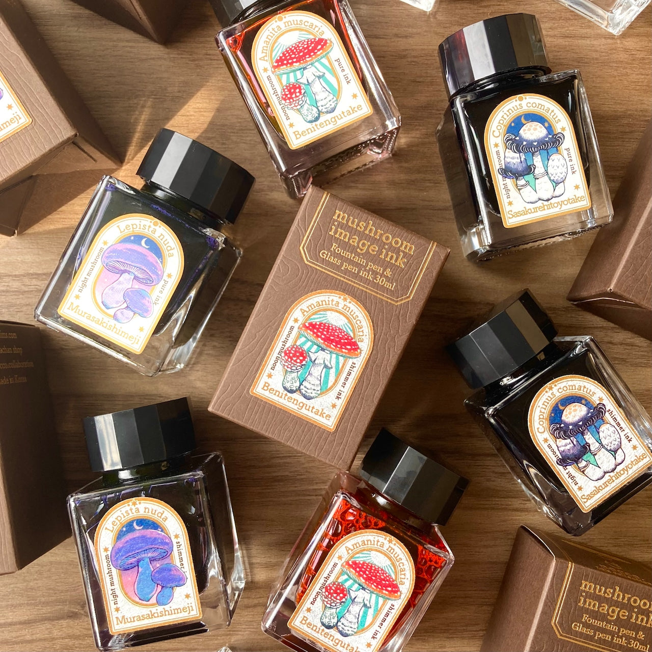 Mushroom-themed ink bottles with labels on a wooden surface