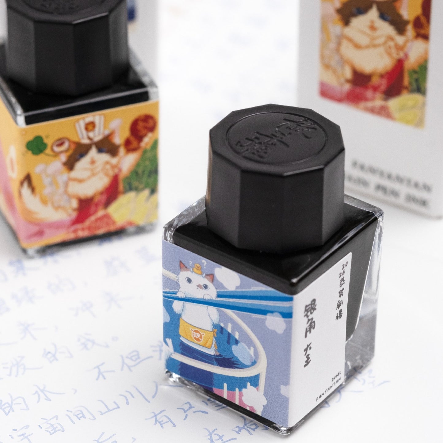 Two fountain pen ink bottles with cat themed label illustrations