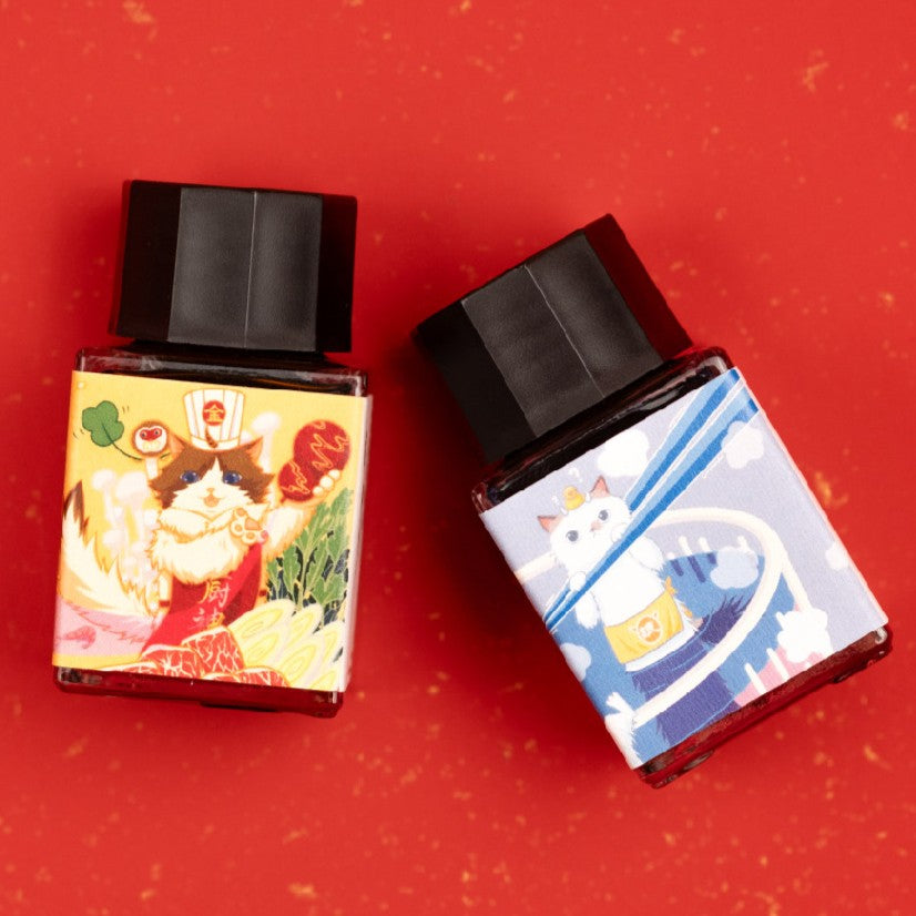 Two bottles of cat themed inks on red background with gold speckles