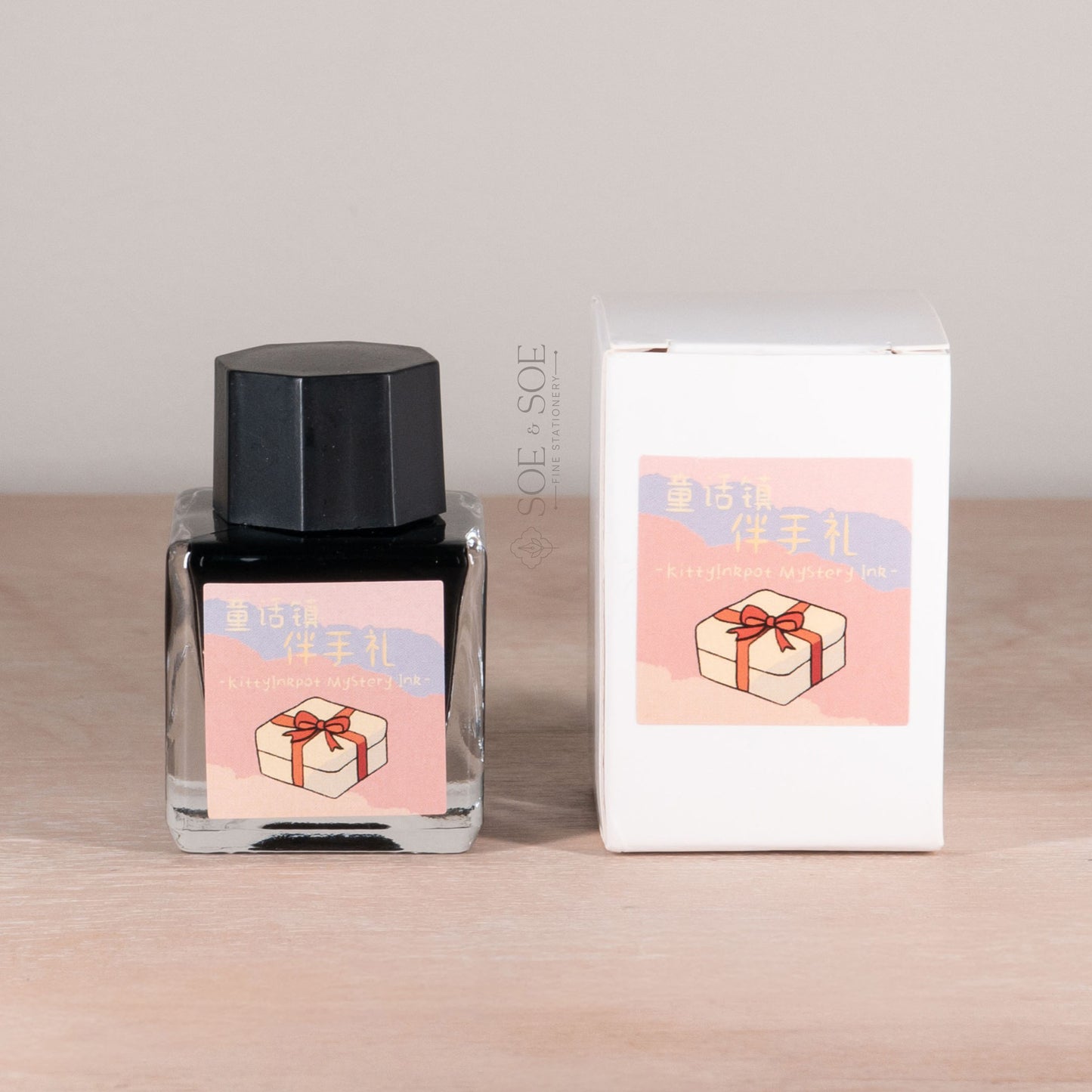 Ink bottle and packaging with a gift box design on a wooden surface