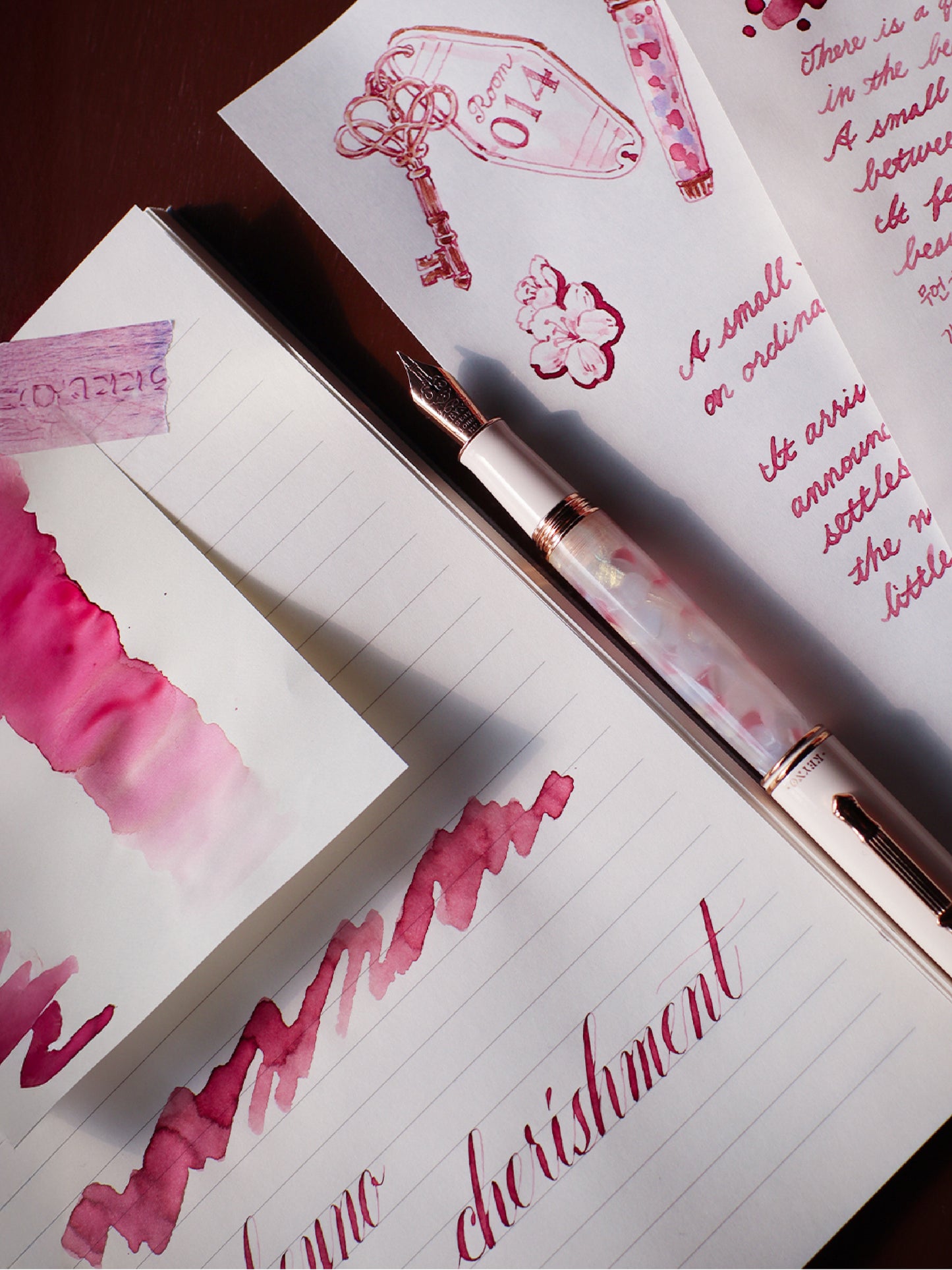 Notebook with pink calligraphy and a fountain pen on top