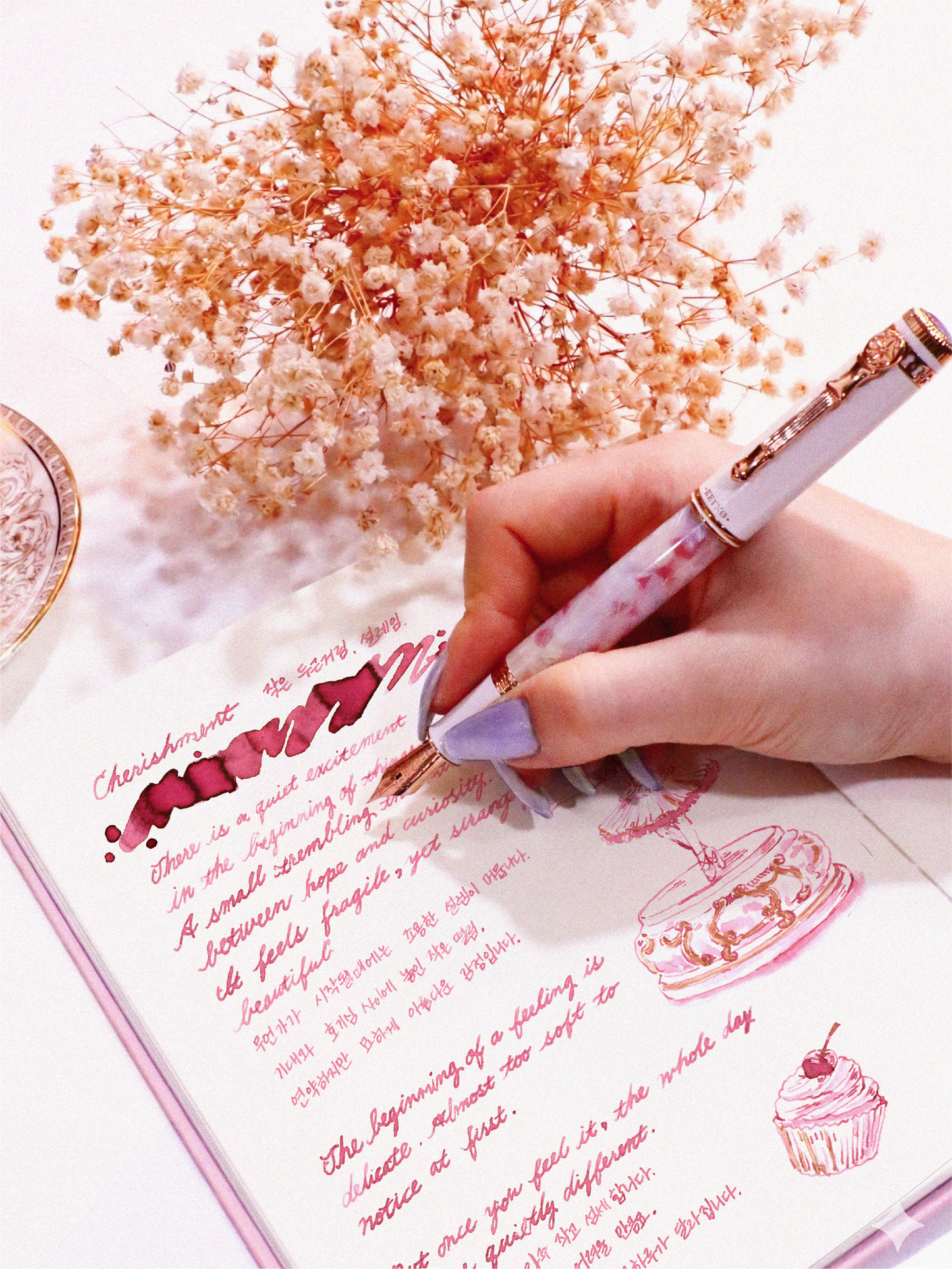 Hand holding a fountain pen over a notebook with floral decorations