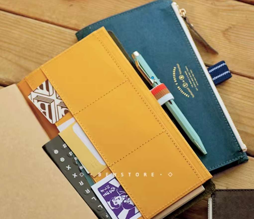 Stack of notebooks with a pen on a wooden surface