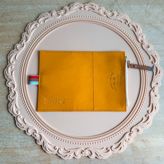 Mustard yellow kraft paper wallet on a decorative white plate with a light wooden background