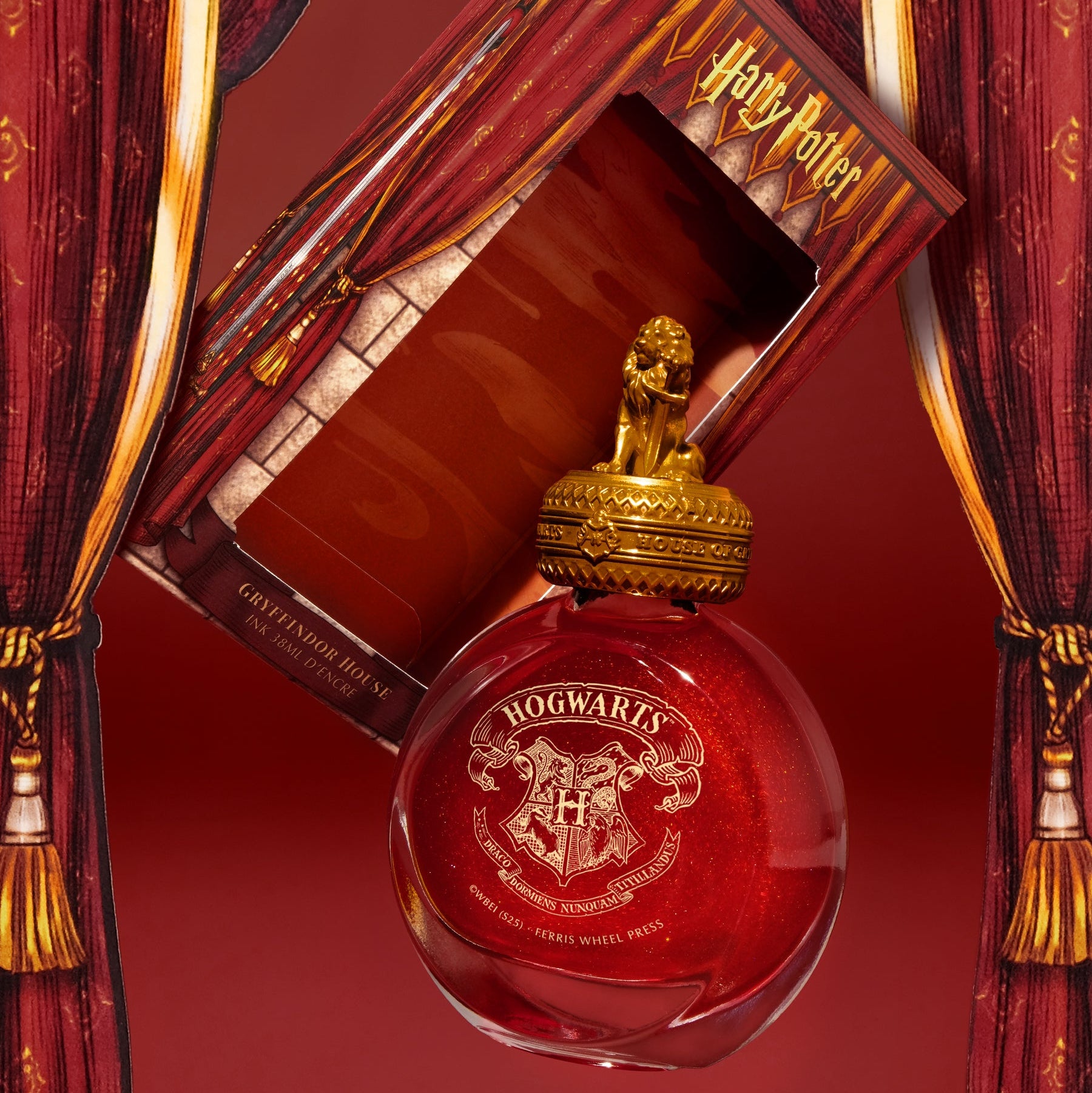 Red ink bottle with gold cap in a decorative box against red curtains