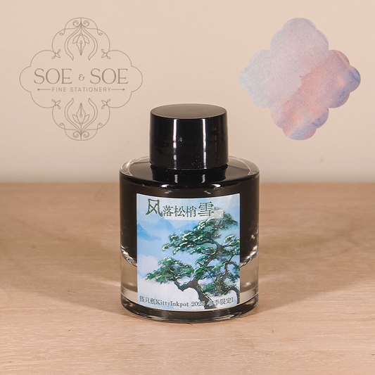Bottle of seasonal kitty inkpot ink with a tree design label on a wooden surface, featuring the 'SOE & SOE' brand.