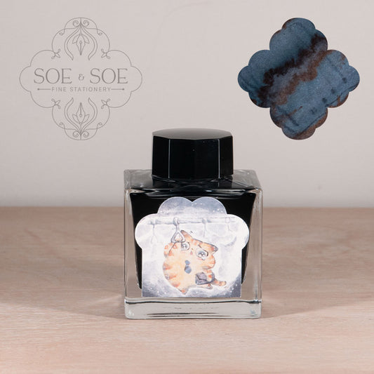 Ink bottle with label with chubby cat illustration on a wooden surface, featuring 'SOE & SOE' branding.