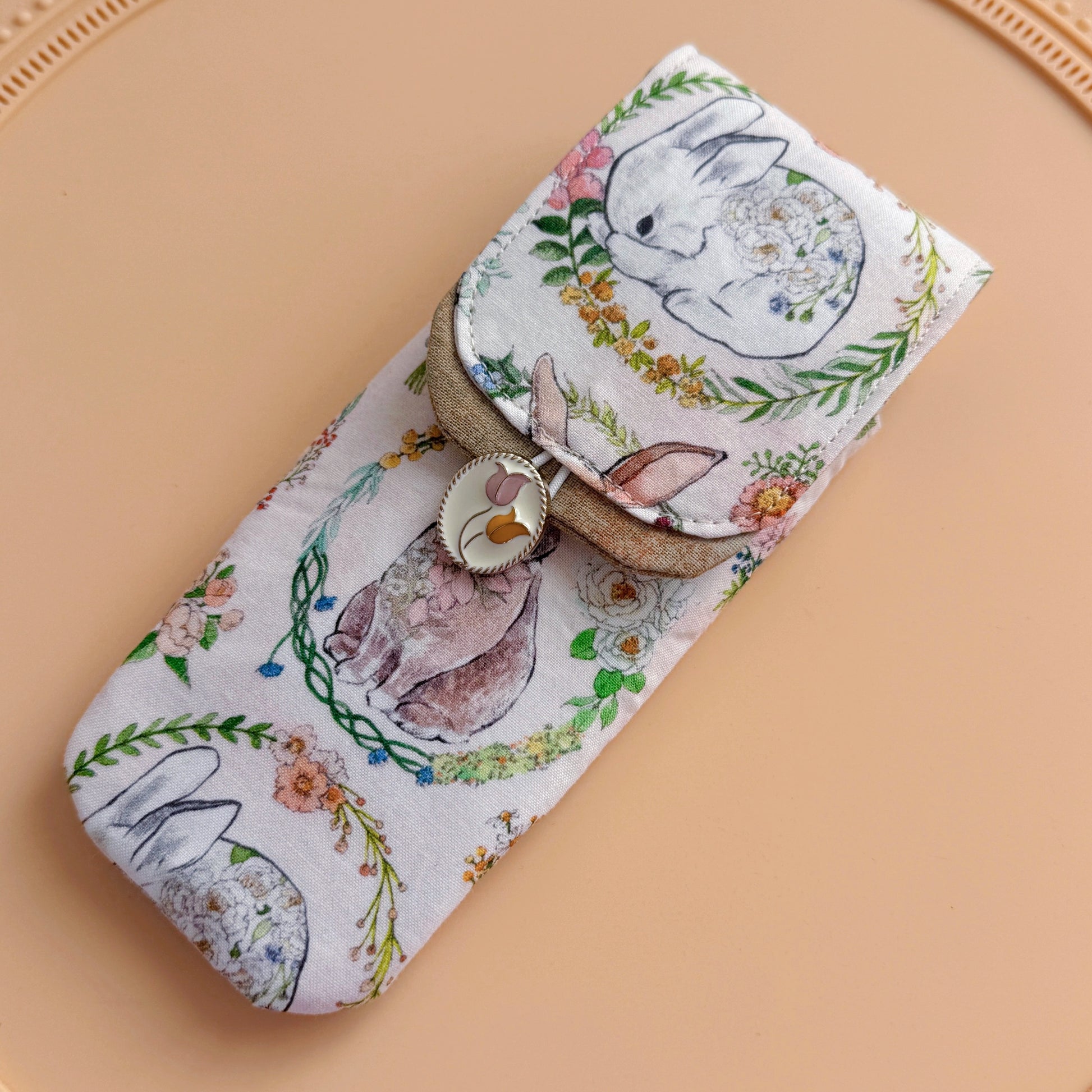 Floral and rabbit-patterned pouch on a beige background