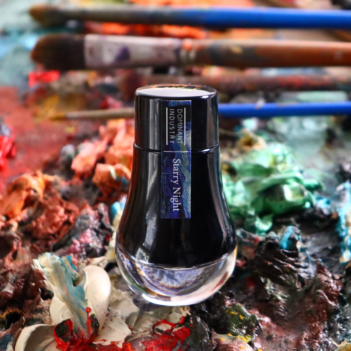 Ink bottle labelled 'Sherry Night' on a textured surface with brushes and paint.
