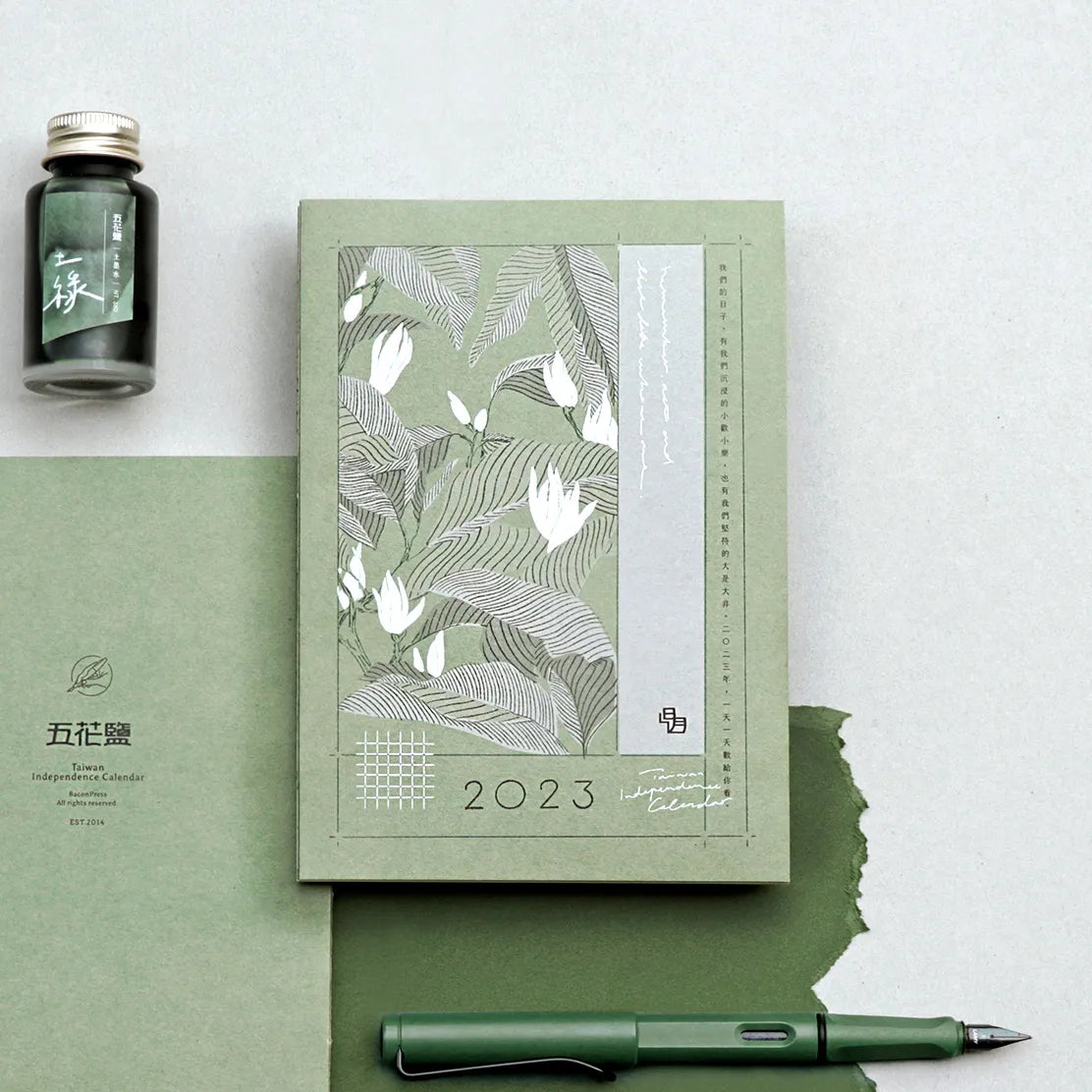 2023 planner with floral design, pen, and ink bottle on a light gray background