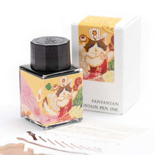 Fountain pen ink bottle with decorative packaging featuring a cat illustration, next to its box on a white background.