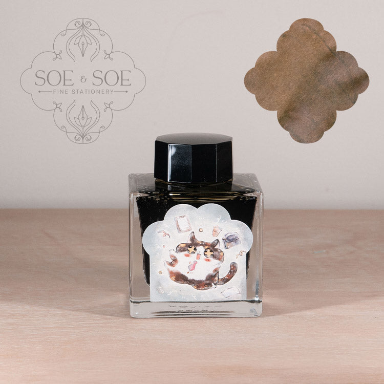 Ink bottle with label with chubby cat illustration on a wooden surface, featuring 'SOE & SOE' branding.