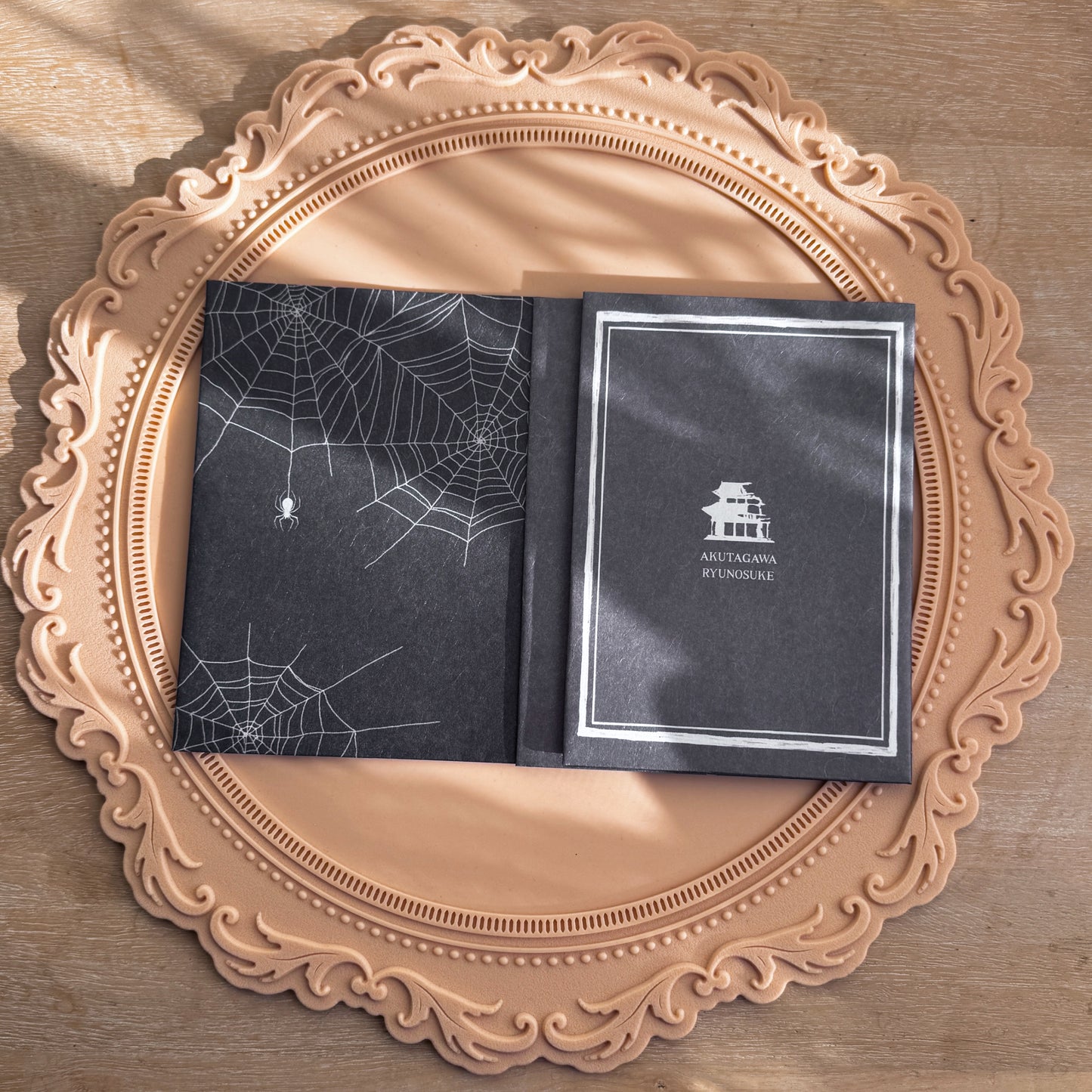 Washi paper book covers with spider web design on one and sihouette of traditional Japanese house on the other