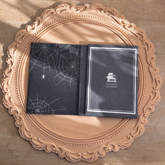 Washi paper book covers with spider web design on one and sihouette of traditional Japanese house on the other