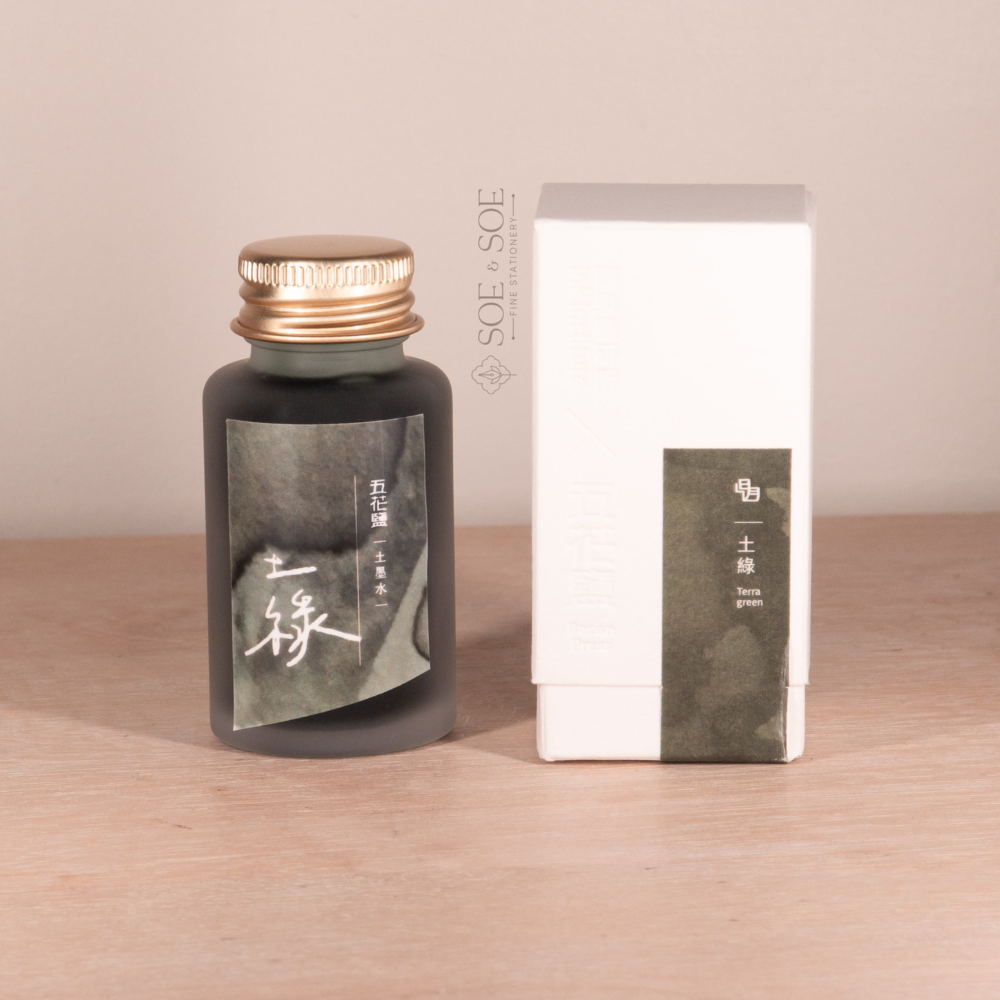 Fountain pen ink bottle and packaging with 'SOE & SOE' branding on a wooden surface.