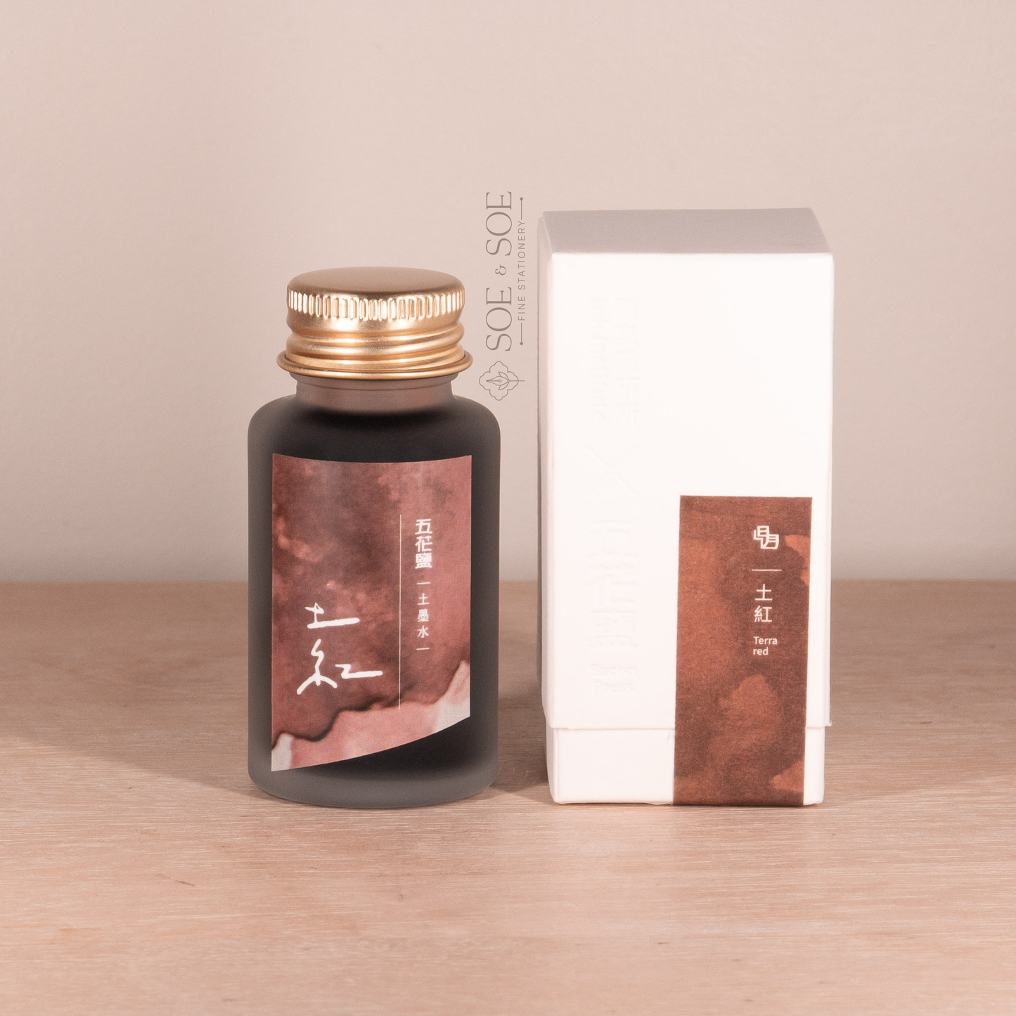 Fountain pen ink bottle and packaging with gold cap on a wooden surface