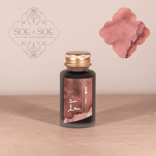 Ink bottle with a pink label on a wooden surface, featuring the 'SOE & SOE' brand.