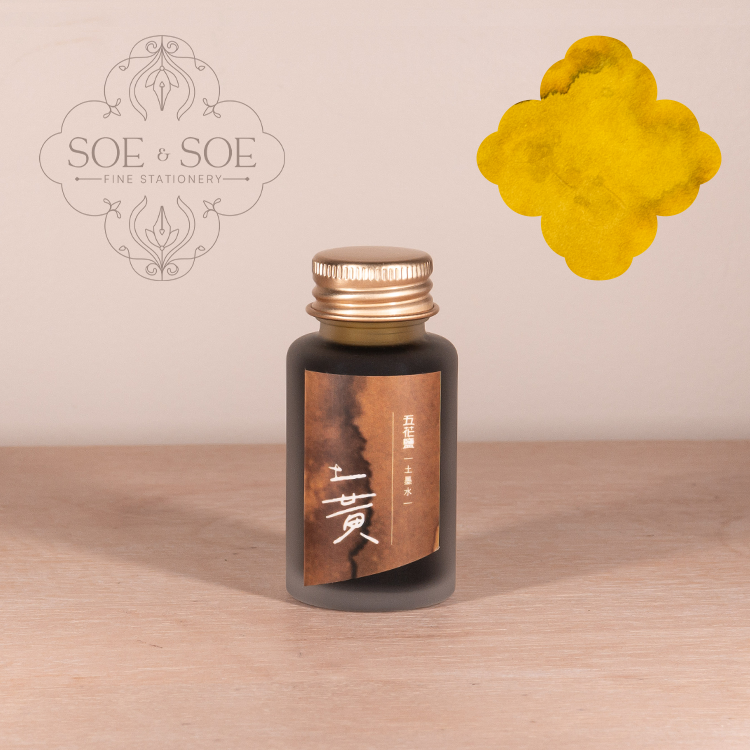 Bottle of ink with a gold cap on a wooden surface, featuring the 'SOE & SOE' brand.