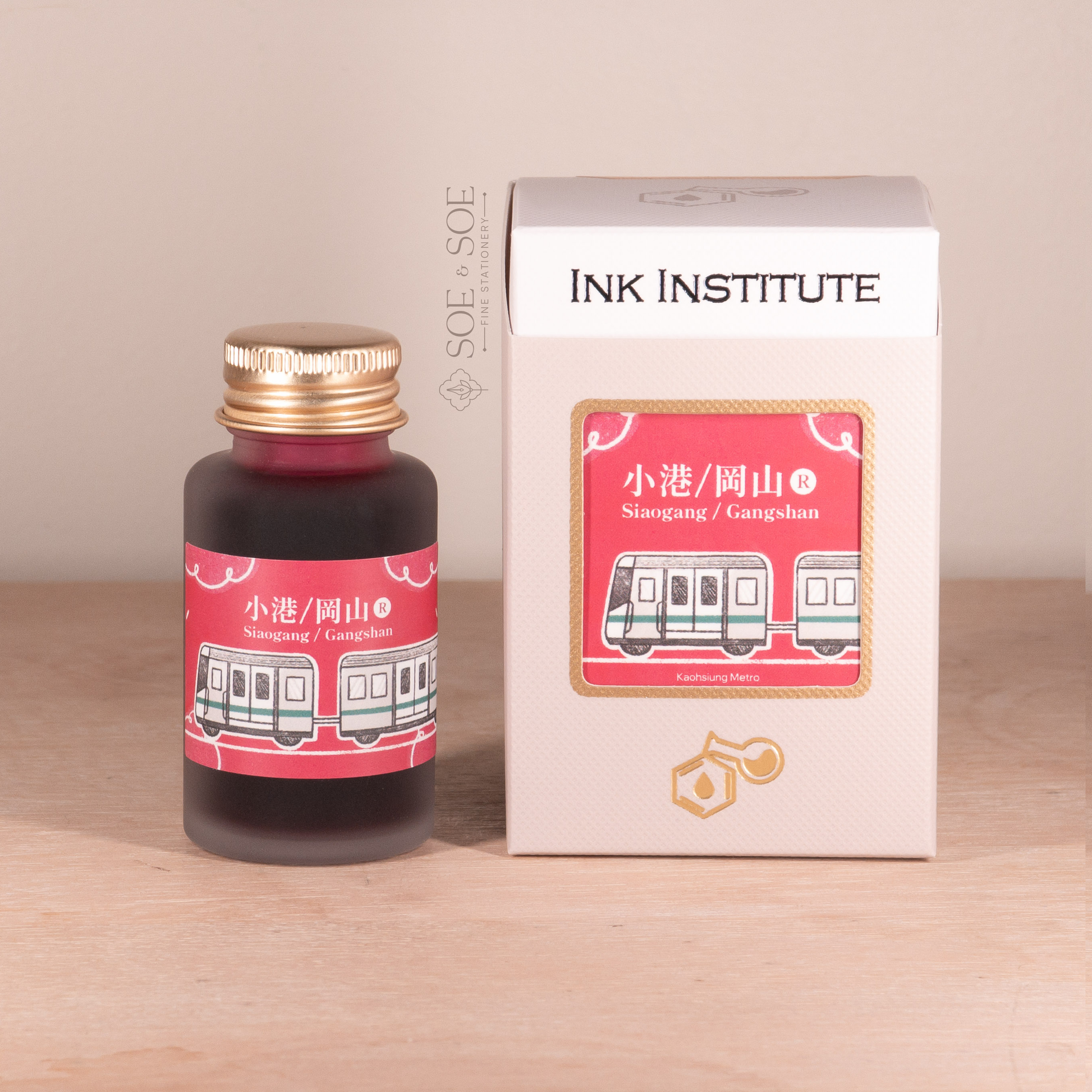 Pink Ink bottle and packaging with 'Ink Institute' branding on a wooden surface.