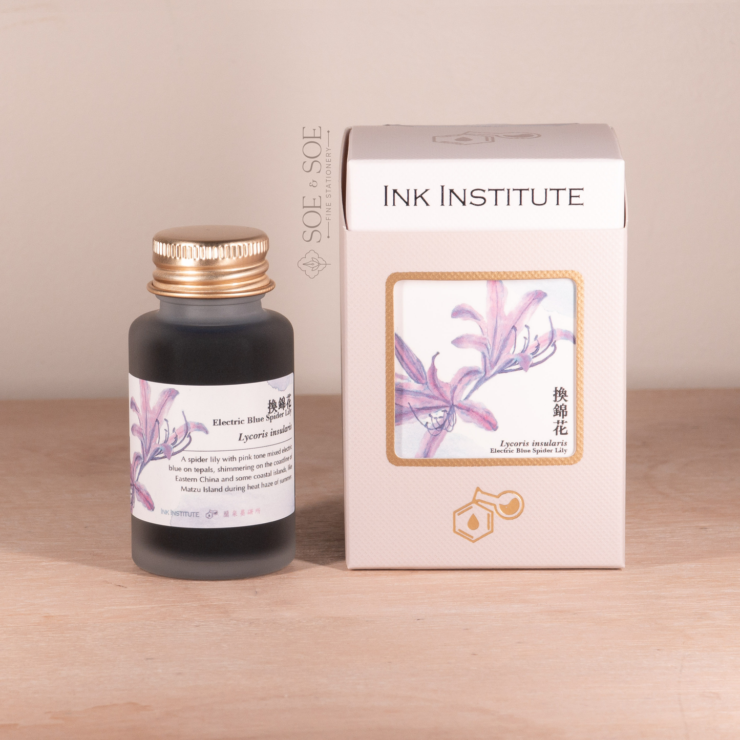 Ink bottle and packaging with 'INK INSTITUTE' branding on a wooden surface.