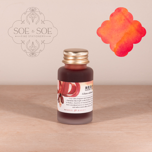 Bottle of ink with a gold cap on a wooden surface, featuring the SOE & SOE brand.