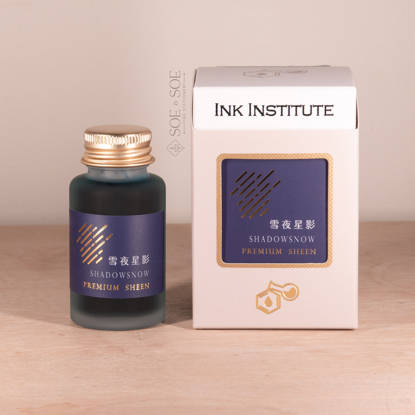 Ink bottle and packaging of Ink Institute on a wooden surface with a beige background
