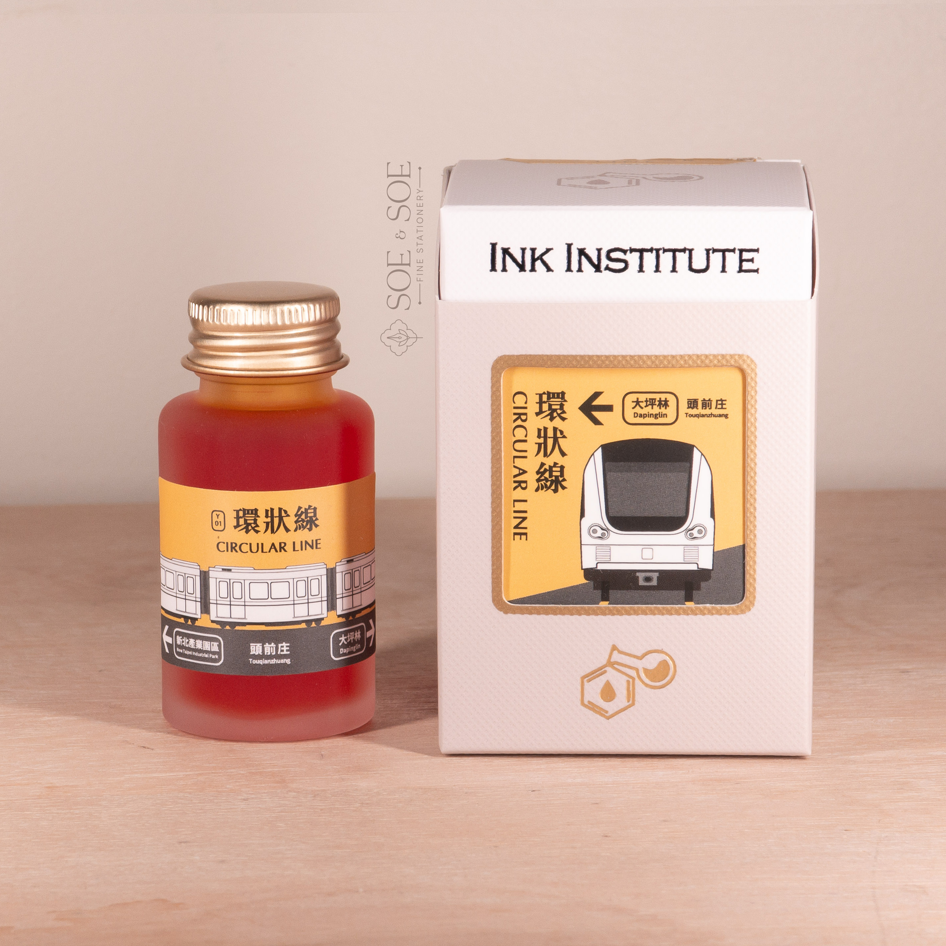 Ink bottle and packaging with 'Ink Institute' branding on a wooden background