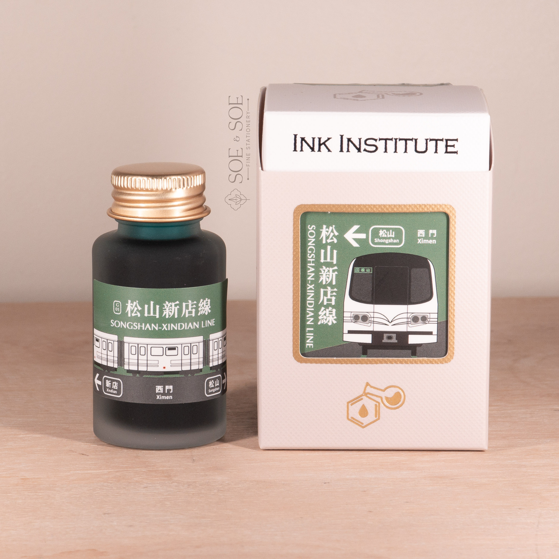 Ink bottle and packaging with 'Ink Institute' branding on a wooden surface.