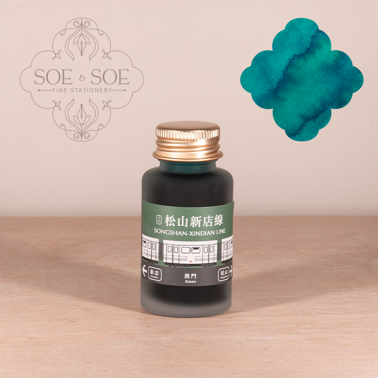 Bottle of Ink Institute ink with a green label on a wooden surface, featuring the SOE & SOE brand.