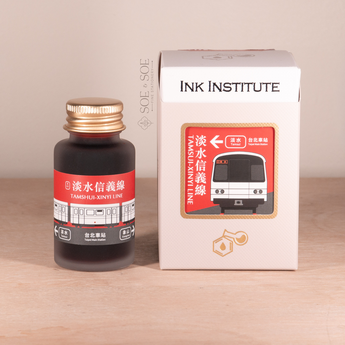 Ink bottle and packaging with 'Ink Institute' branding on a wooden surface.
