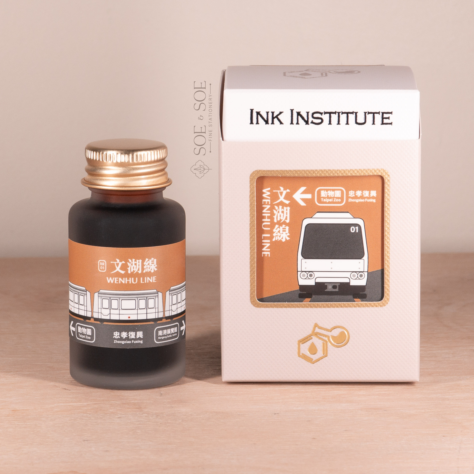 Ink bottle and packaging with 'Ink Institute' branding on a wooden surface.