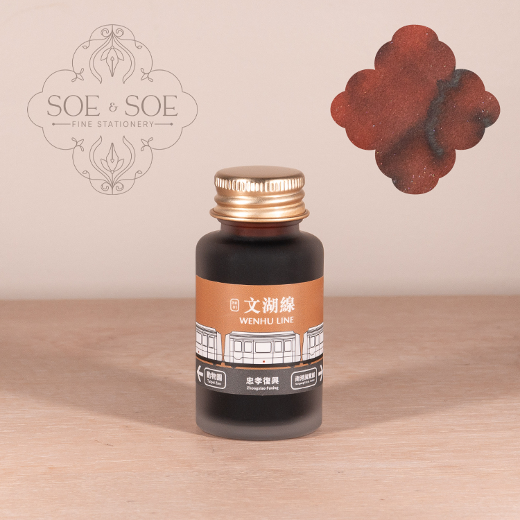 Ink bottle with a gold cap on a wooden surface, featuring the 'SOE & SOE' brand.