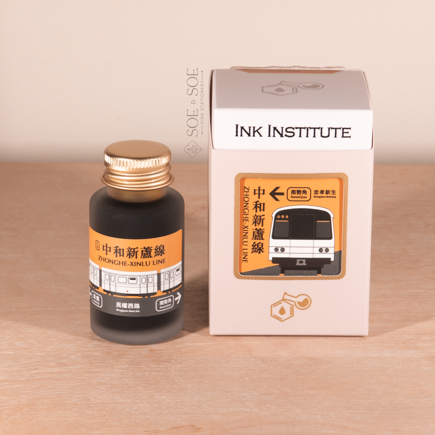 Ink bottle and packaging with 'Ink Institute' branding on a wooden surface