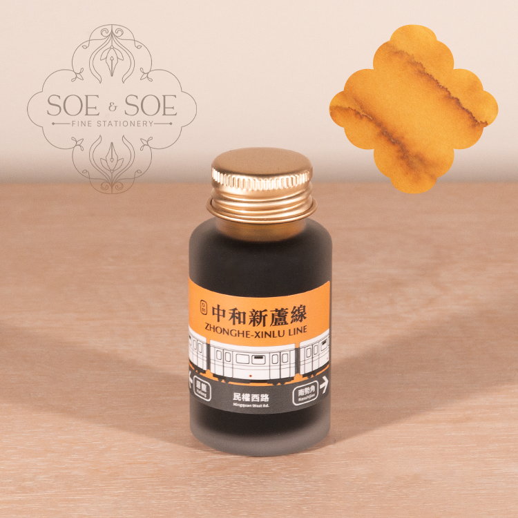 Bottle of ink with a gold cap on a wooden surface, featuring the 'SOE & SOE' brand.
