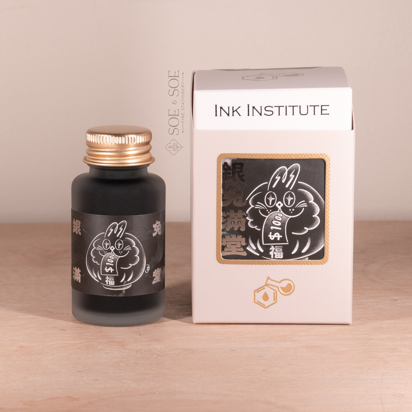 Ink bottle and packaging with 'Ink Institute' branding on a wooden surface.