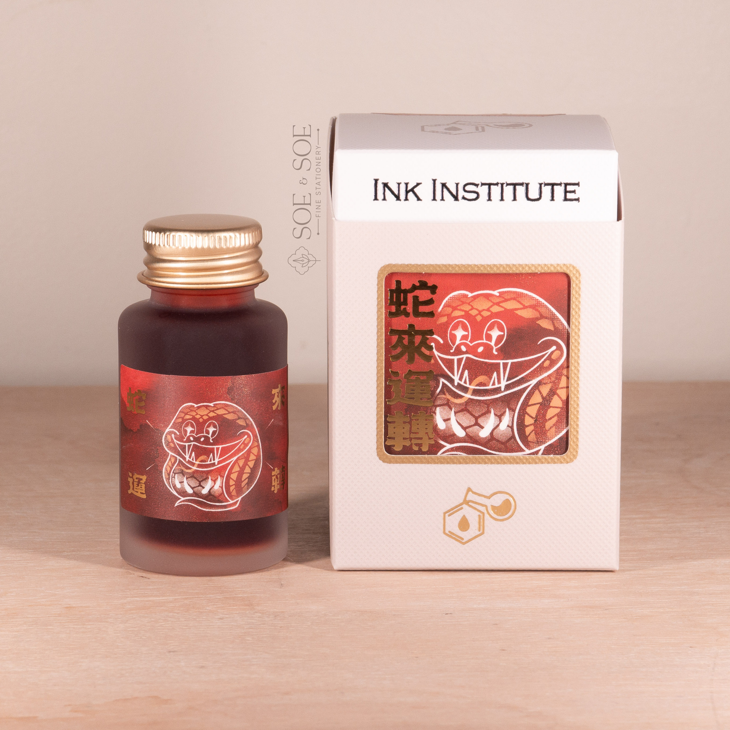 Bottle and packaging of Ink Institute product on a wooden surface with a beige background