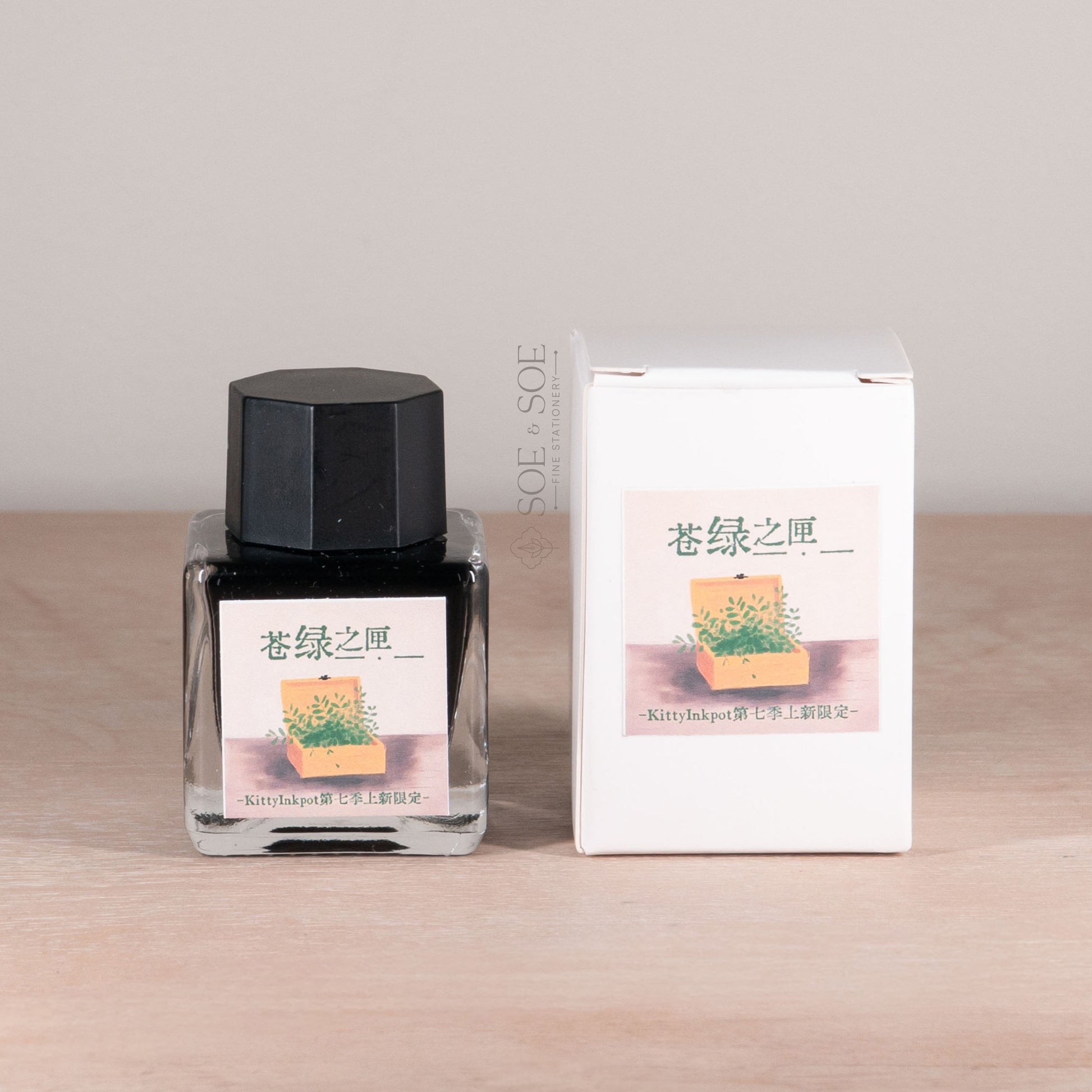 Ink bottle and packaging on a wooden surface with a neutral background
