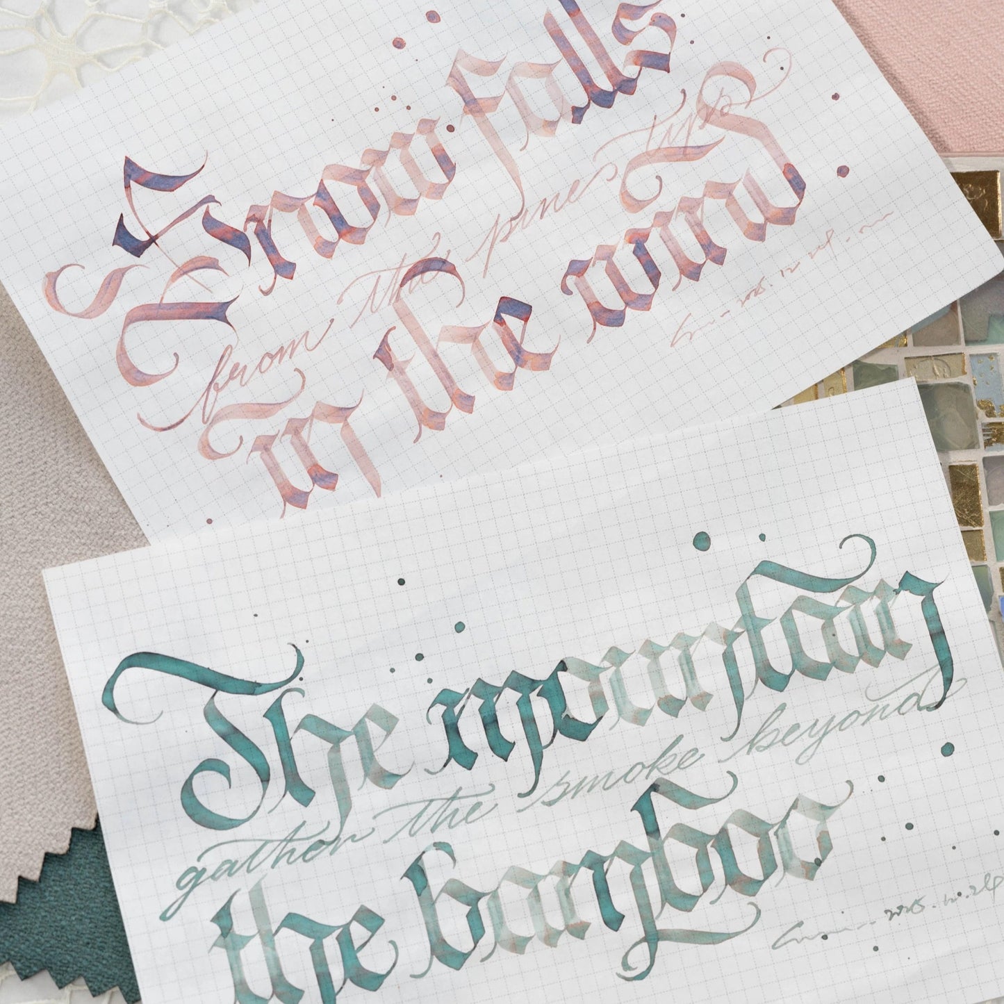 Two sheets of paper with decorative calligraphy text on a textured surface.