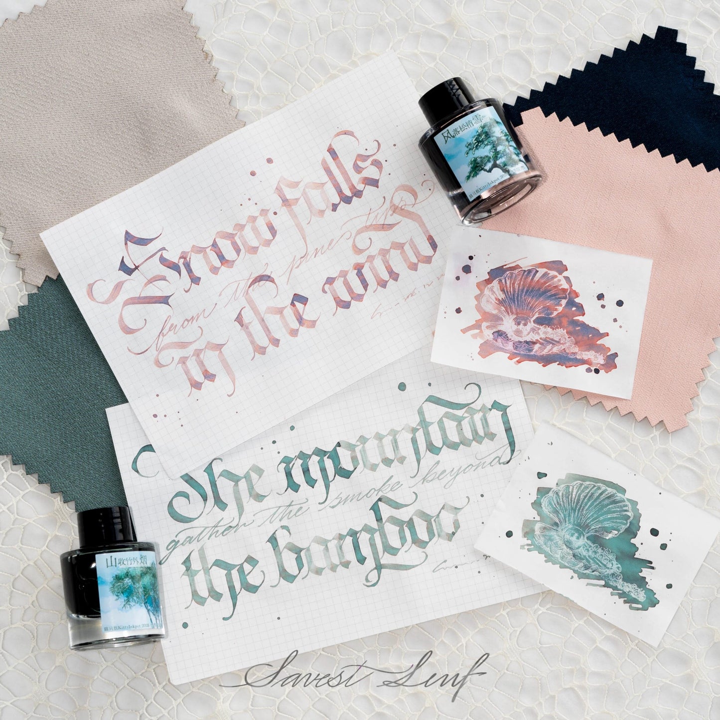 Calligraphy samples with kitty inkpot ink bottles on a textured surface