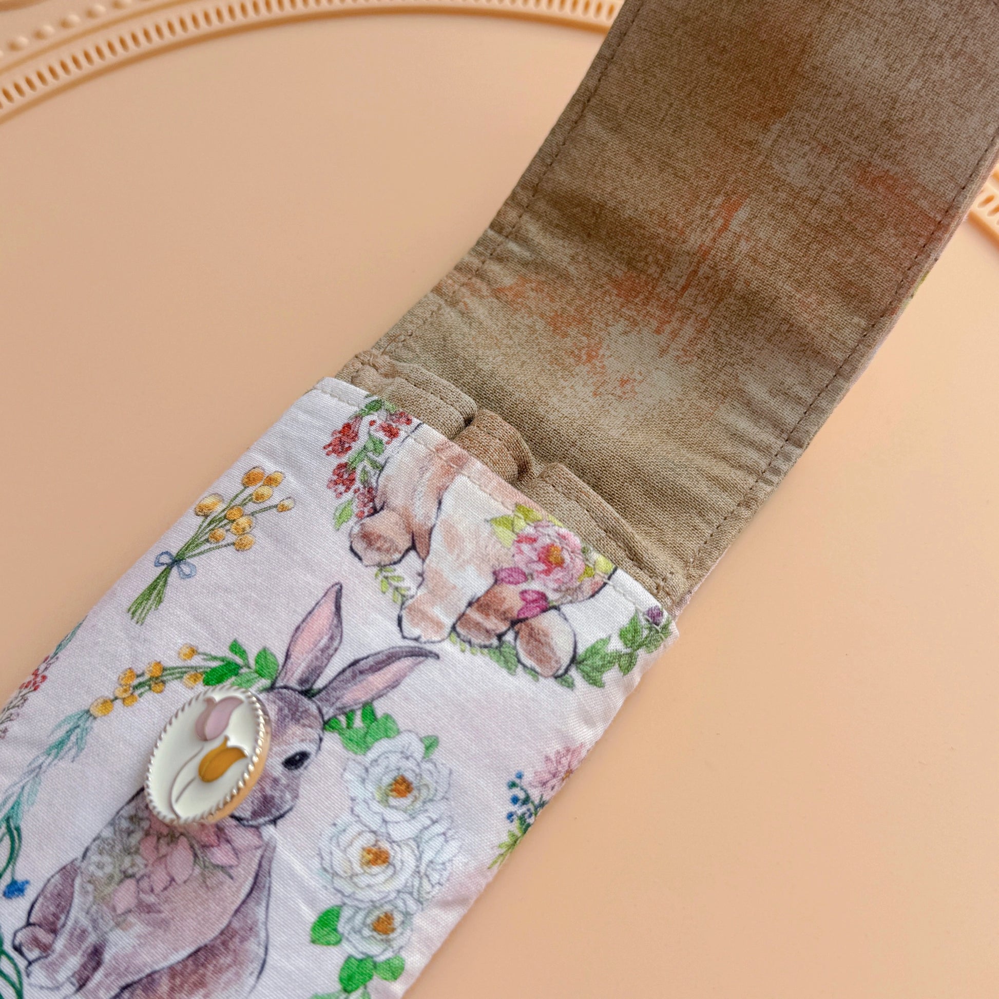 Open fabric pen case with bunny and flower pattern on a beige background
