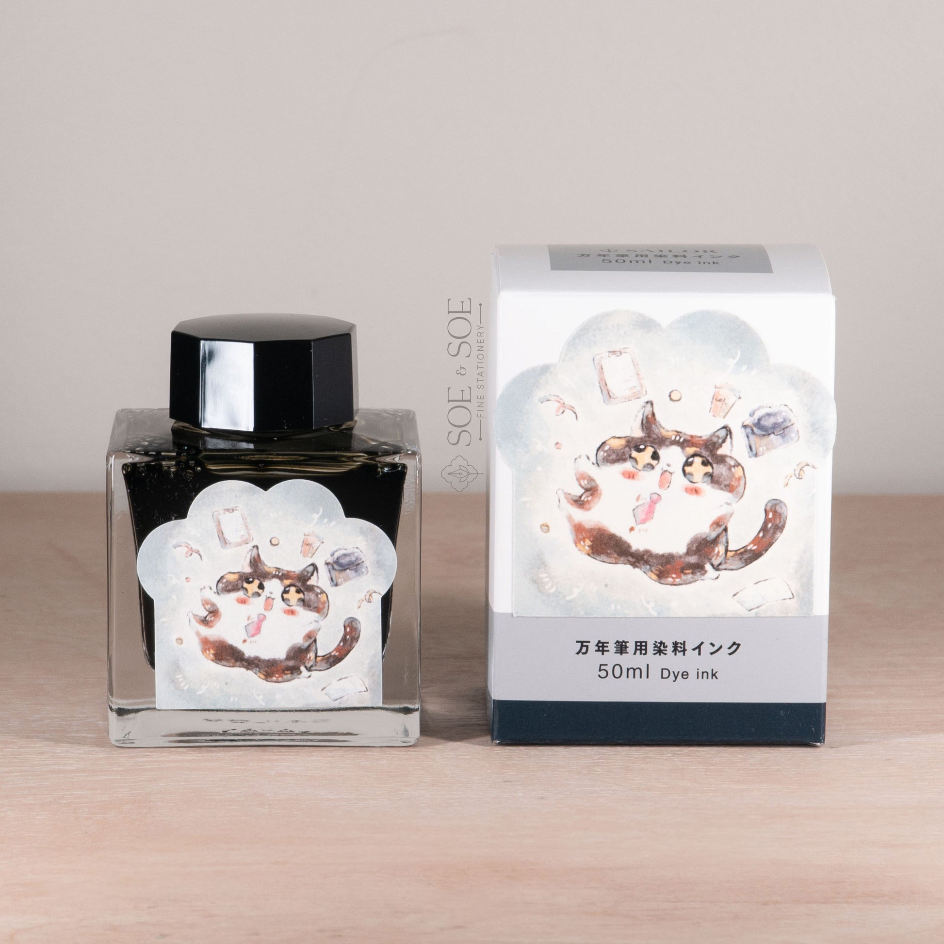 Ink bottle and packaging with a design of a cat with tie on a wooden surface.