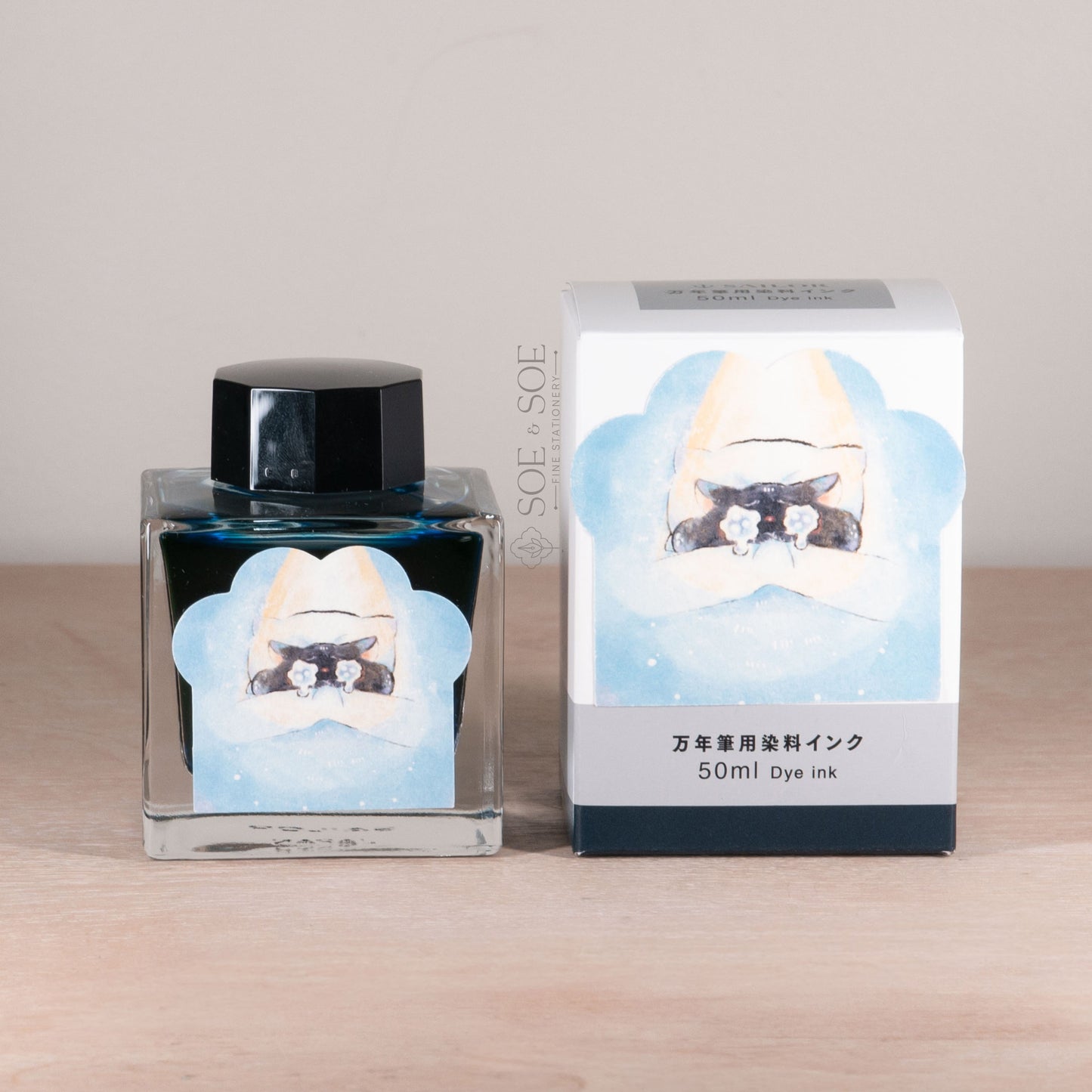 Ink bottle and packaging with a chubby cat in bed design on a wooden surface
