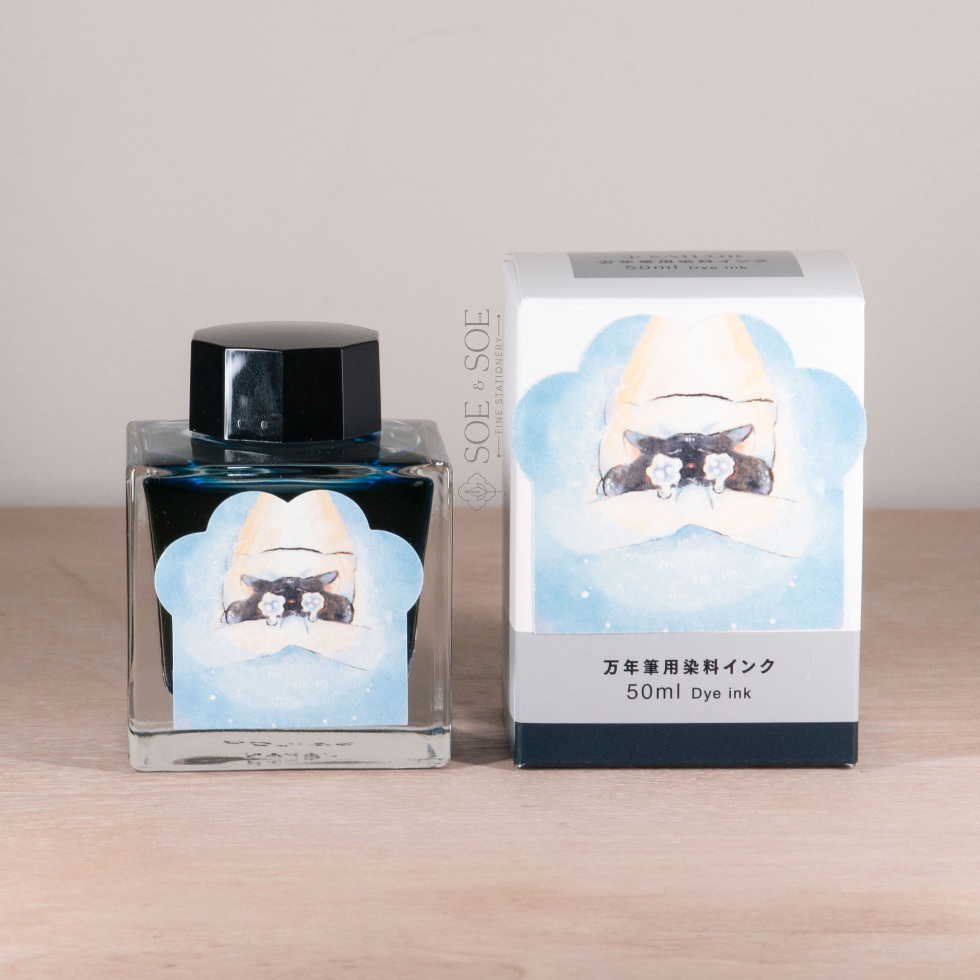 Ink bottle and packaging with a chubby cat in bed design on a wooden surface