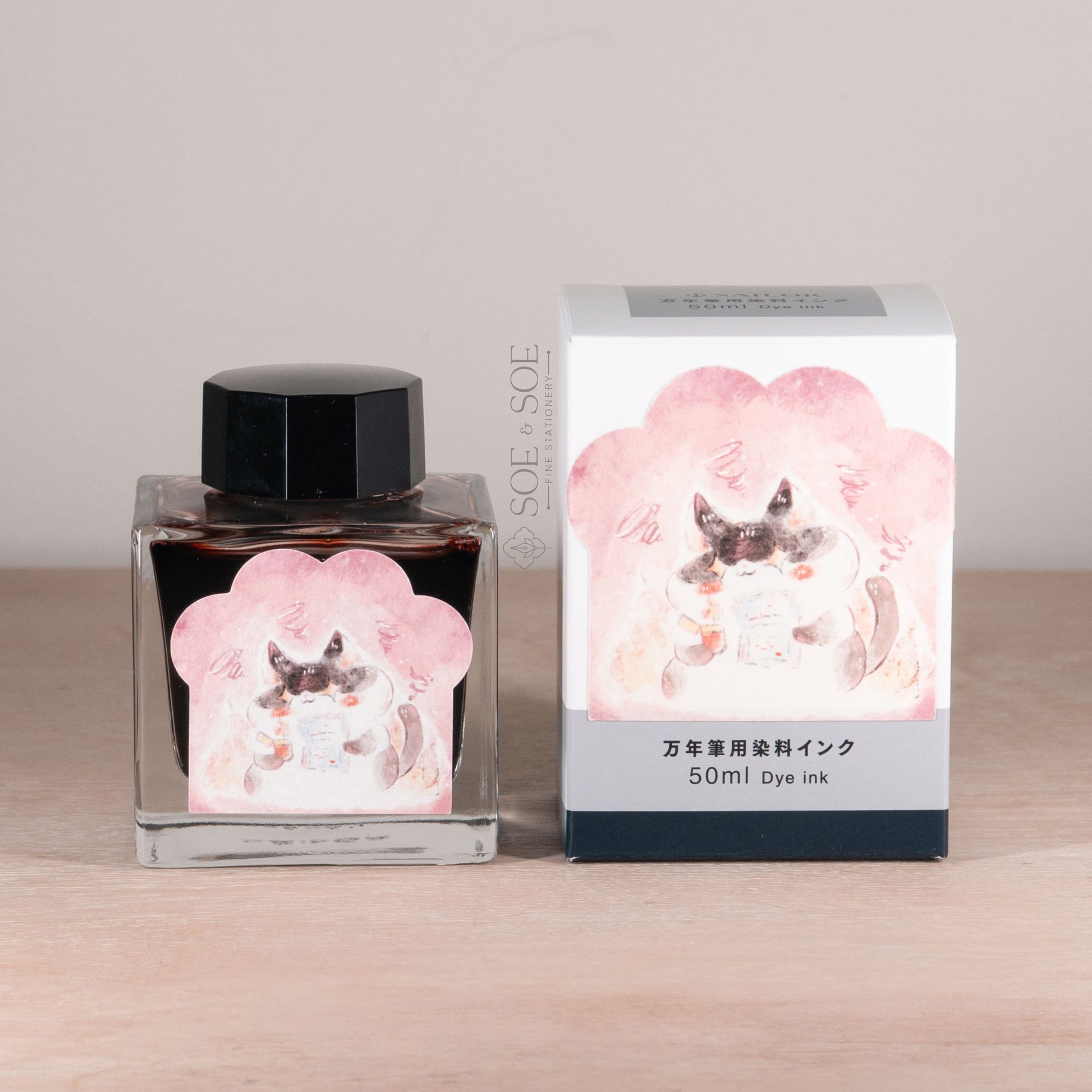 Ink bottle and packaging with paw shaped sticker illustration of a cat on a wooden surface