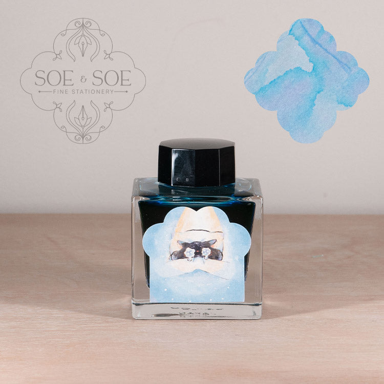 Ink bottle with label with chubby cat illustration on a wooden surface, featuring 'SOE & SOE' branding.