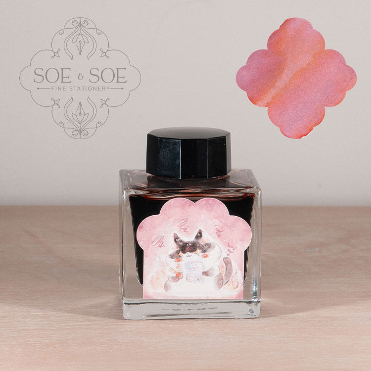 Ink bottle with label with chubby cat illustration on a wooden surface, featuring 'SOE & SOE' branding.